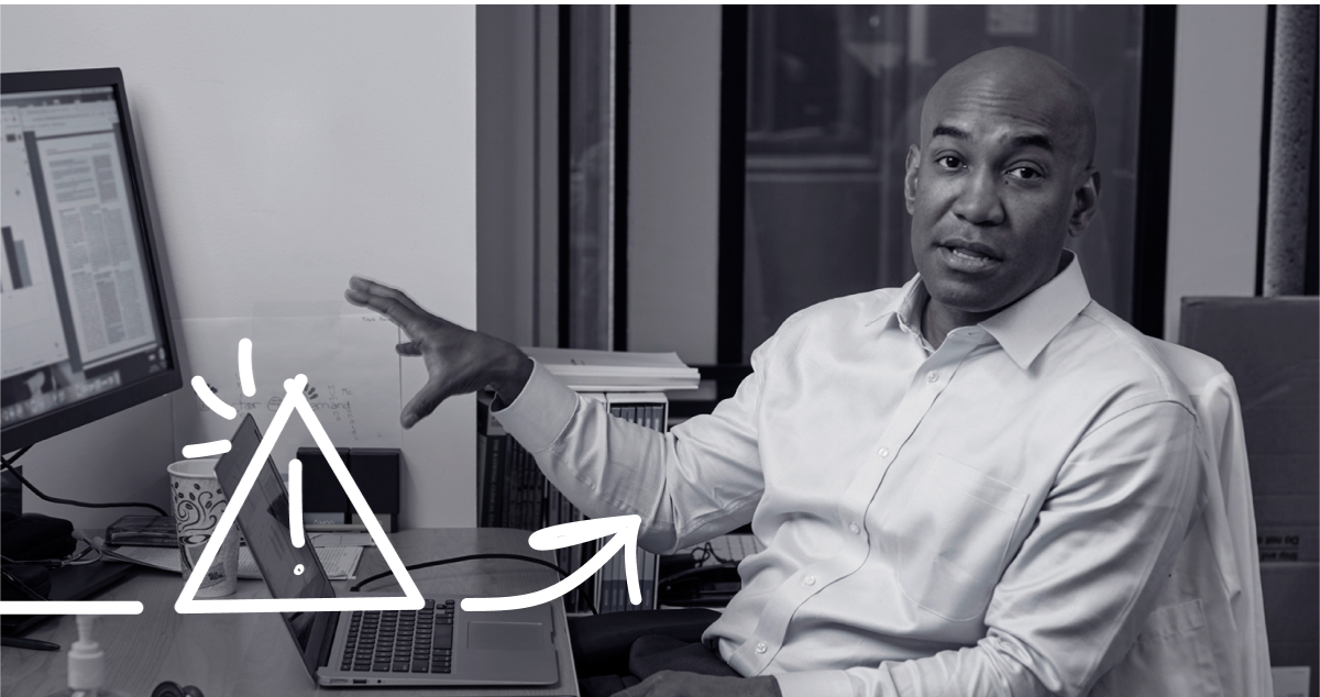 a person sitting at a desk with a laptop and a computer