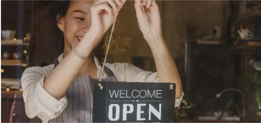 a woman holding an open sign