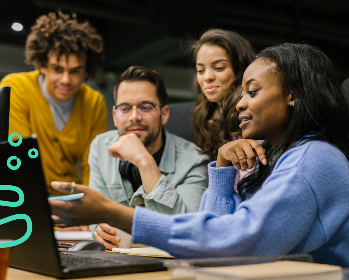 a group of people sitting at a table looking at a laptop