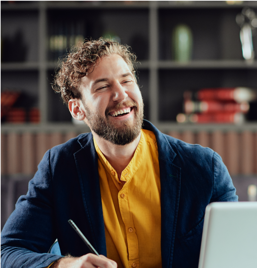 a man smiling while holding a pen