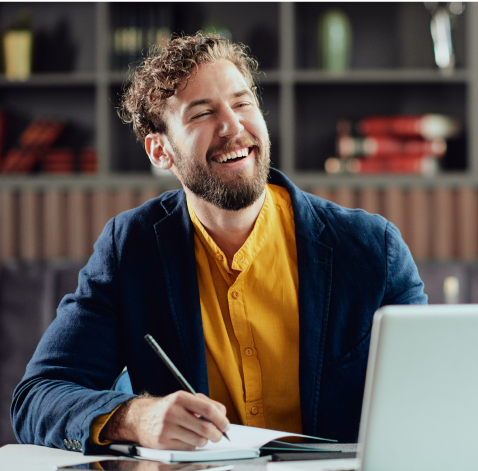 a man smiling while holding a pen