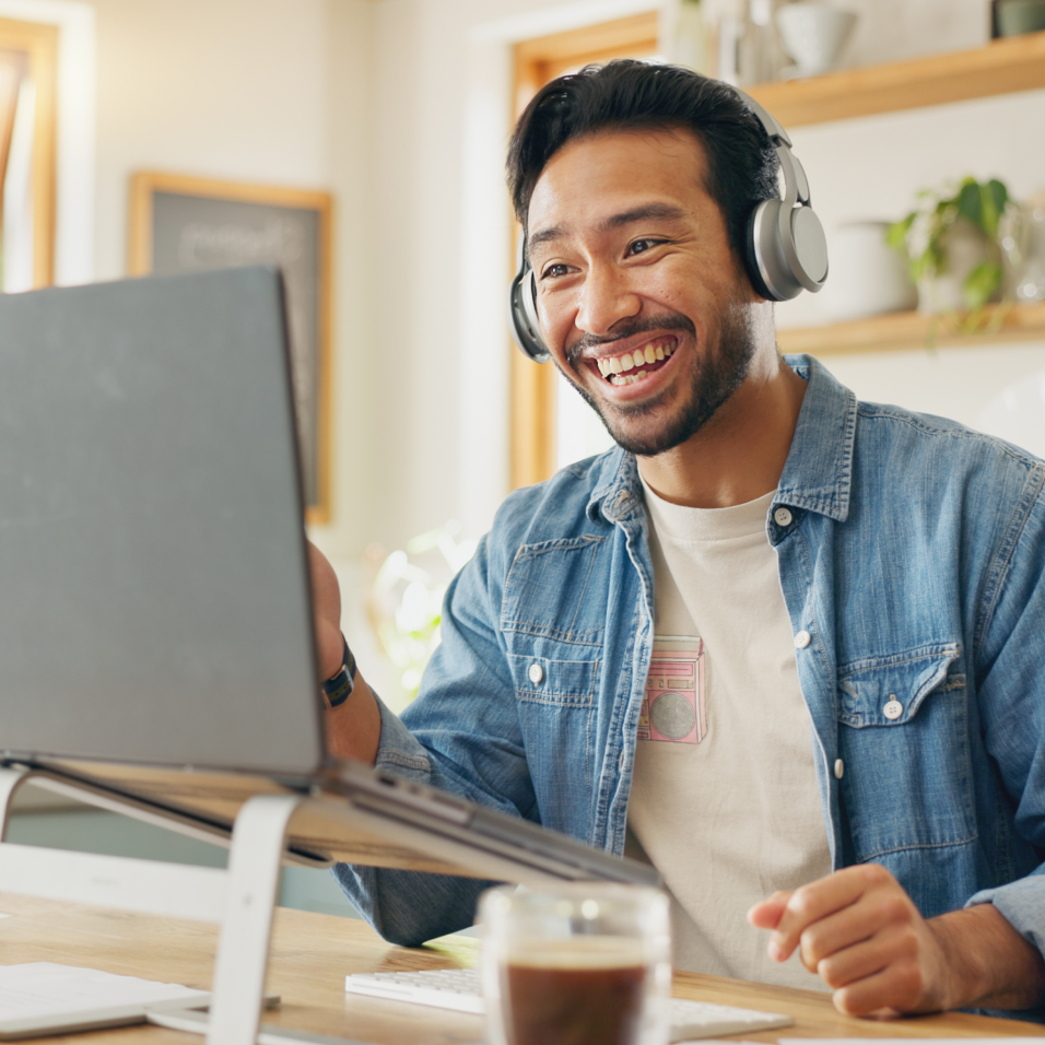 a person wearing headphones and sitting at a table with a laptop