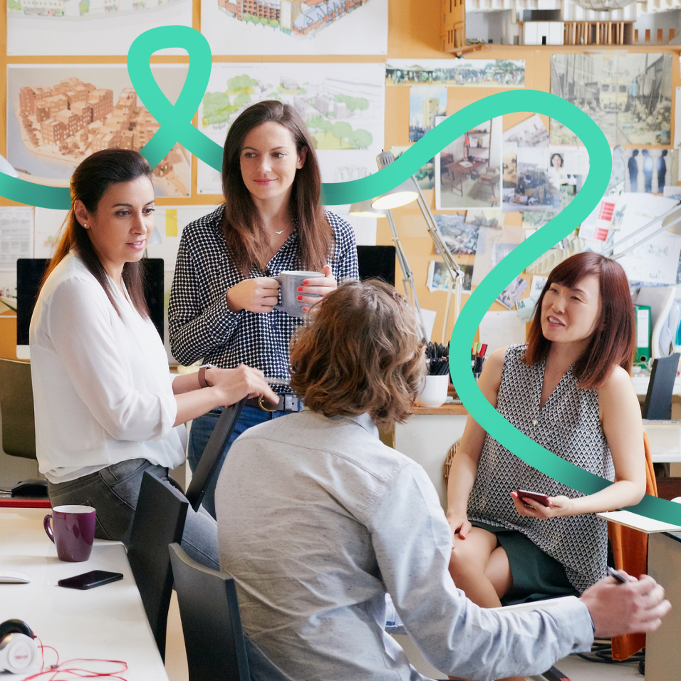 Group of people having a casual discussion in a creative office space with design boards on the wall.