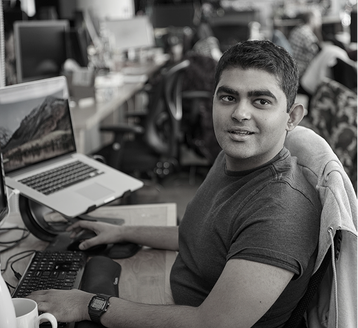 man working on open space with two laptops at his desk