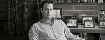 sitting man with family portraits behind him